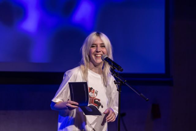 Persoon op het podium met een microfoon bij open podium Hub