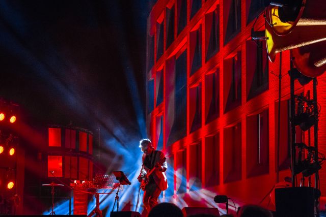 Persoon die gitaar aan het spelen is op een podium